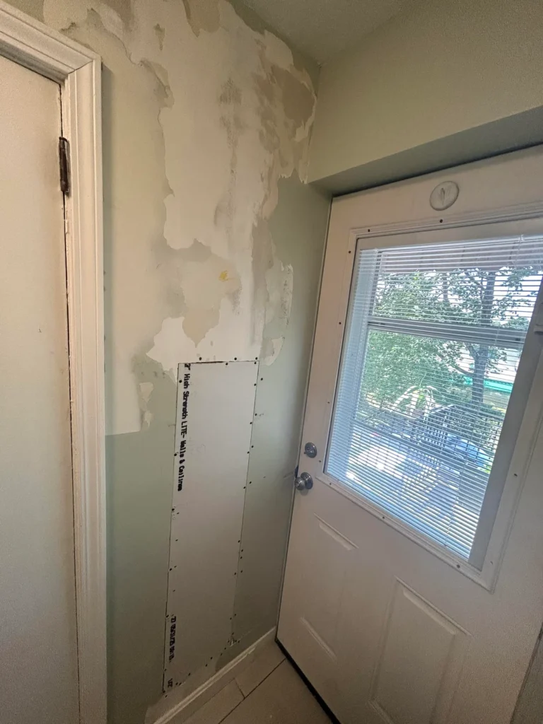 New drywall patch panel installed beside an exterior door